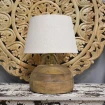 lampa stołowa vivien z drewna mango z jasnym abażurem na tle rzeźbionego panelu