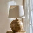 lampa drewniana kula w aranżacji z jasnym abażurem na drewnianym stoliku