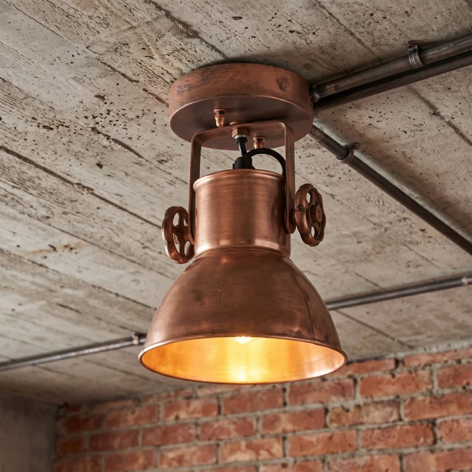 miedziana lampa sufitowa zamontowana na betonowym suficie miedzy rurami styl loft