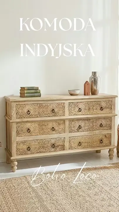 Prezentacja wideo: Szeroka komoda indyjska o długości 145 cm z jasnego, naturalnego drewna mango, wyposażona w sześć szuflad o frontach ozdobionych subtelnym, rzeźbionym wzorem ornamentowym, z metalowymi uchwytami w kształcie pierścieni, osadzona na toczonych nóżkach, udekorowana książkami, ceramiką i dekoracyjnym wazonem na blacie, zaprezentowana w jasnym wnętrzu na tle białej ściany, stojąca na podłodze przy dużym plecionym dywanie z juty – Meble Indyjskie / Boho / Orientalne